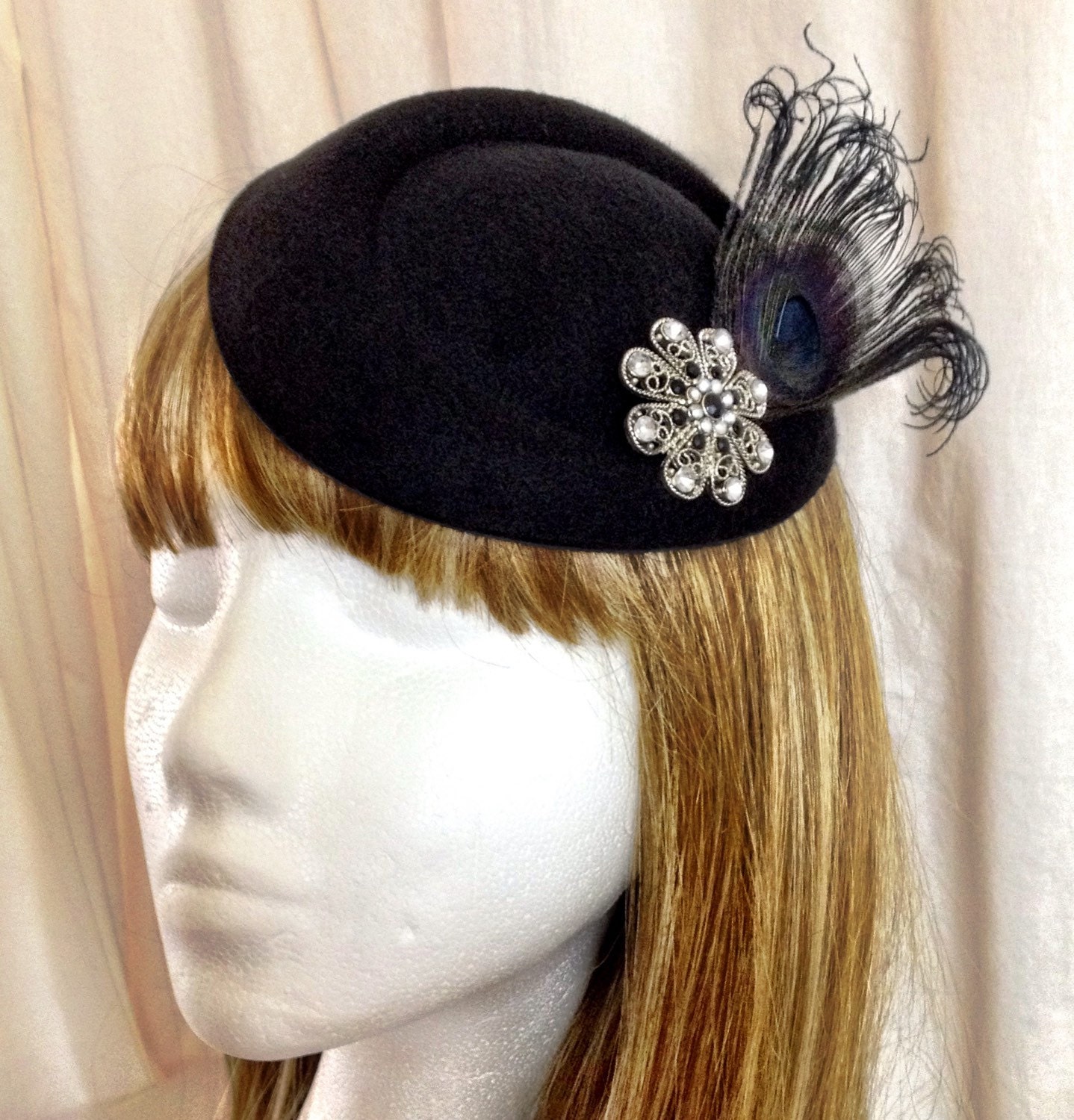 Black pillbox hat with black peacock feather and silver flower