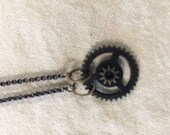 Simple steampunk gear on a brass chain with black beads.  Length-17" PENDANT