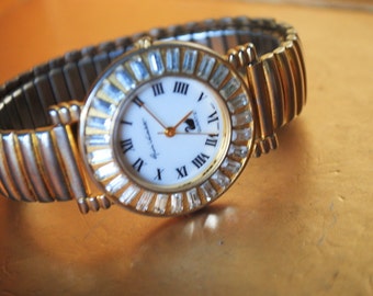 Art deco vintage 80s large, round wrist watch with aurora borealis frame and combine metal stretched bracelet. Made by Gloria Vanderbilt.