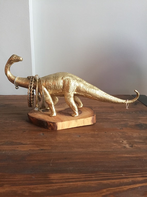 Gold dinosaur jewelry holder on piece of olive wood. (Jewelry tree)