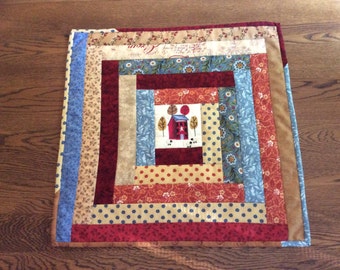 Handmade, quilted log cabin table topper with embroidered center