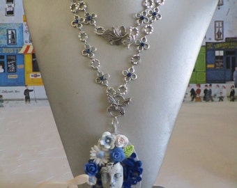 Collier plastron pendentif "Un visage altéré entouré de fleurs"