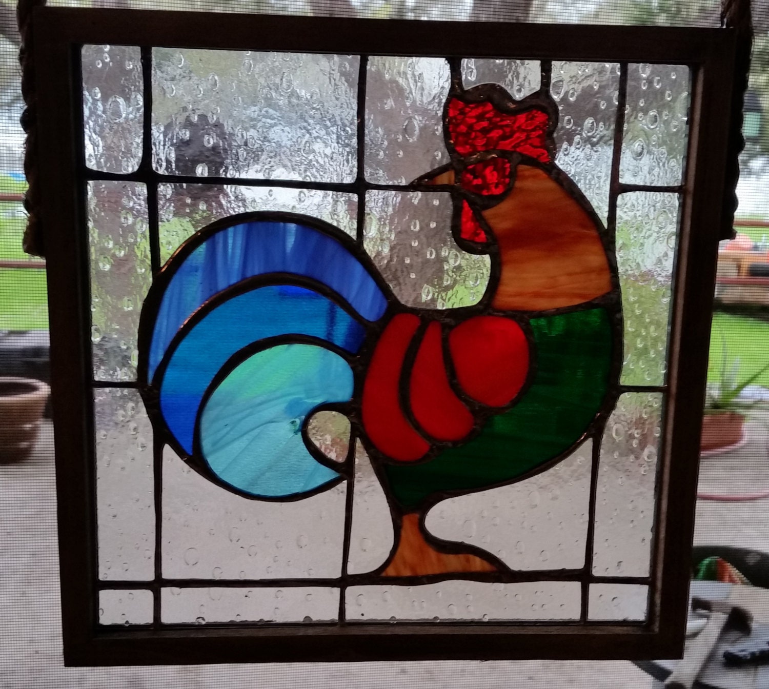Multicolored stained glass rooster set in wood frame with rope