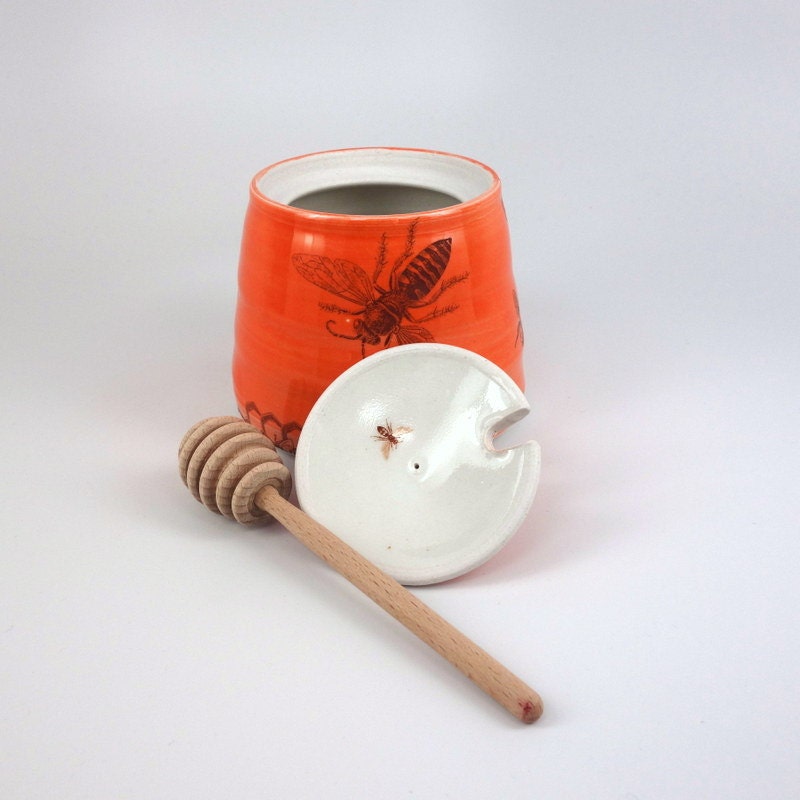 Red glazed porcelain honey pot with bees buzzing and