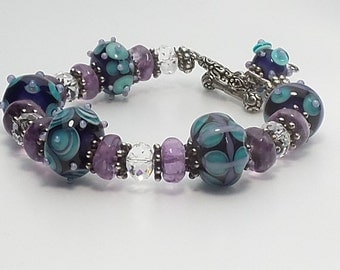 Lavender, turquoise, and dark purple lampwork beaded bracelet embellished with amethyst stones, swarovski crystals and Bali silver.