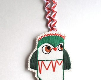 Christmas owl ornament hand embroidered in shades of greens with bright red on cream muslin and cream felt with holiday ribbon loop