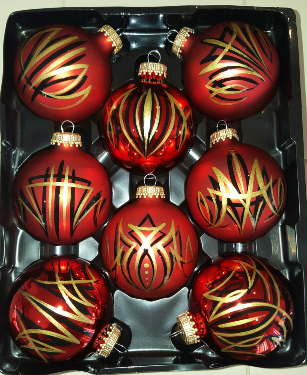 8 red ornaments with gold and black pinstriping