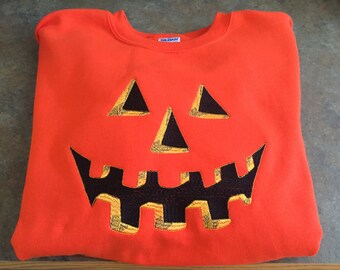 Embroidered pumpkin face adult sweatshirt. Avail. in sizes Med-Xlg. @ this price. Larger sizes available. See below