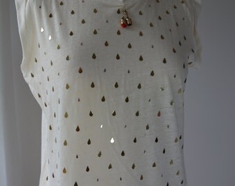 Lightweight cream ladies top with gold pearl-drops and feature charm