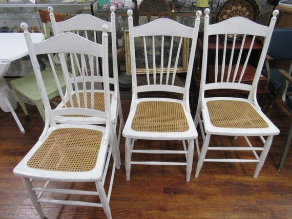 Four white chairs with rattan seats