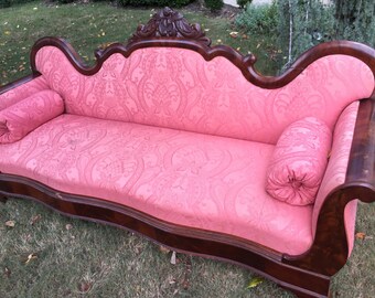 Flame mahogany Victorian sofa with casters. Salmon upholstery. Atlanta Fig House Vintage.