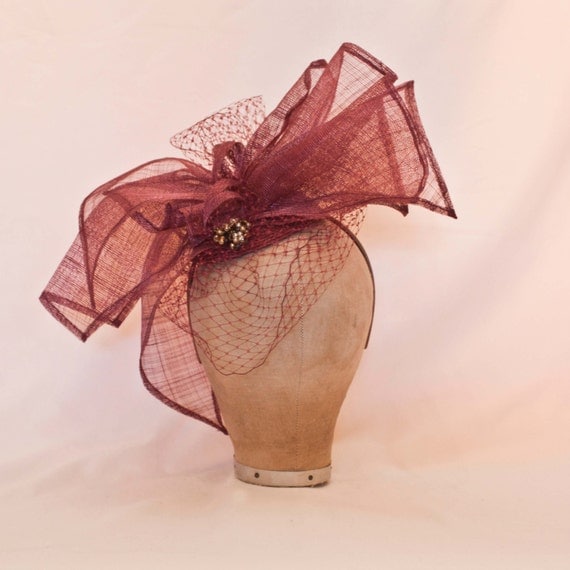 Handmade dusky plum asymmetric bow ladies hat decorated with veil and bead detailing
