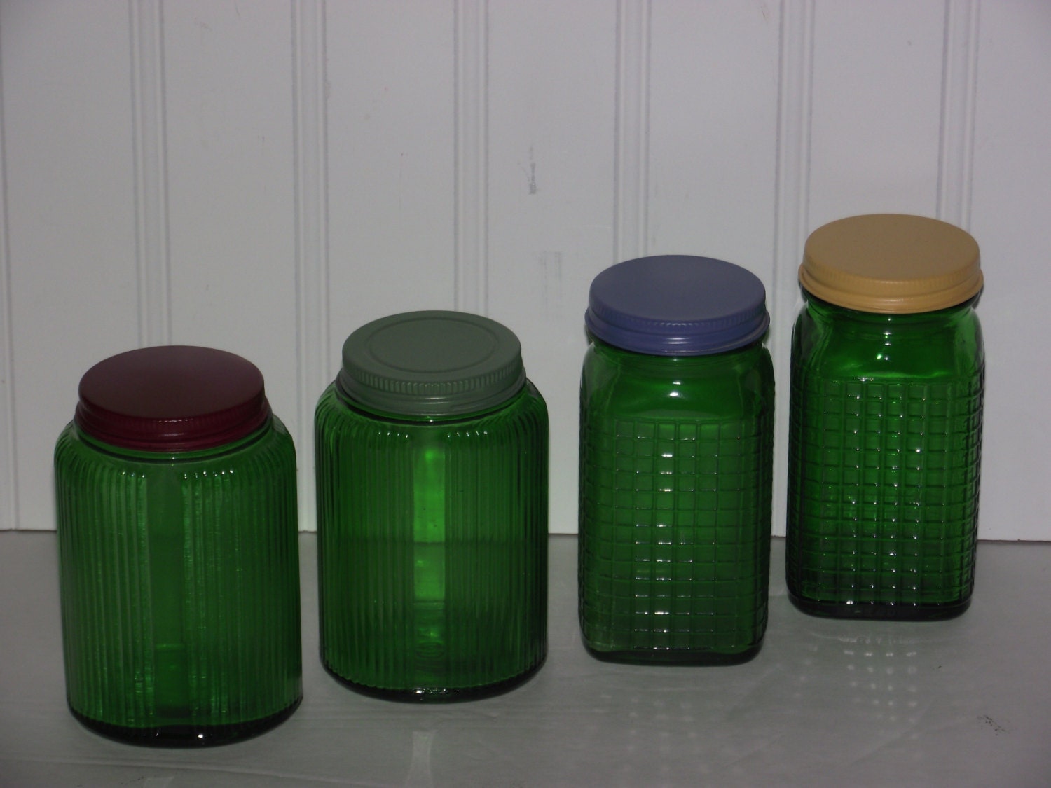 Four vintage Depression Era green glass jars all with