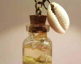 Glass vials with cowry shells on bronze chain
