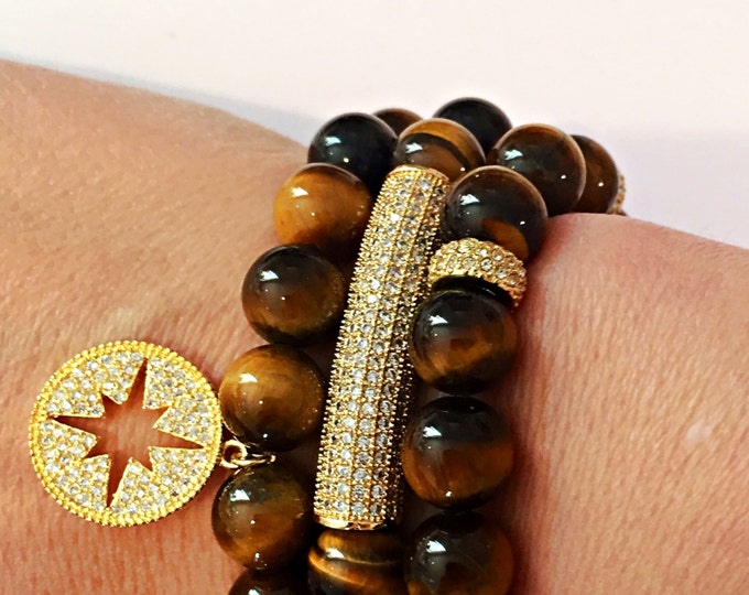 Tigers eye brown 10mm beaded stretch bracelet with a gold crystal rhinestone open starburst disc charm dangling.