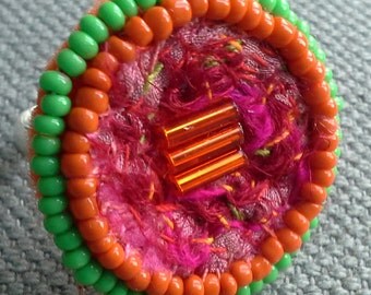 Textile ring, sparkling colours, silks and pearls.