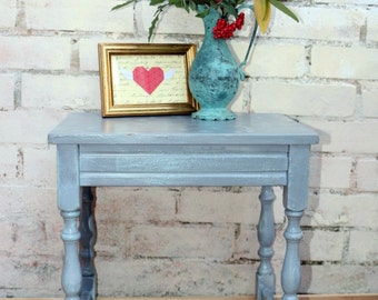 Cute grey painted side table with delicate pattern on top.