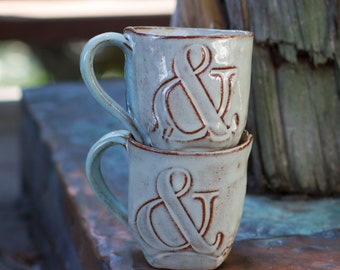 Hand-built mug with a creamy white glaze and ampersand imprinted on the side