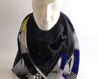 Foulard en voile de laine noir orné d'une bordure réalisée d'un patchwork de conton imprimé graphique N/B, coton fluo, soie bleu et lurex.