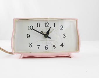 A Pink Bedside Clock - 'General Electric' Clock - Model 7267K - Electric Clock With Alarm - Curved Pink Body - Curved Clear Plastic Face