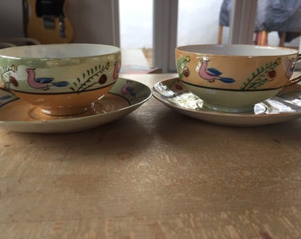 A set of two delicate hand painted tea cup and saucer sets made in Japan circa 1940's