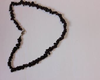 A string around the neck with a shiny brown stones of different sizes