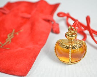Yves Saint laurent dije colgante con cinta roja y estuche ámbar y dorado