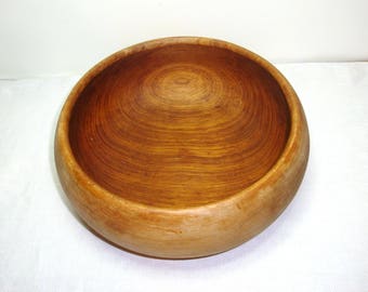 Large wooden bowl with beautiful age rings that generate from the side.. Wood Bowl measures about 10" wide by 4" tall in good used condition