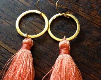 Orange silk tassel earrings on brushed gold hoops.