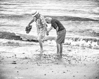 Black & White street photography print, Tourist photo, older couple paddling sea, sandals in hand support, Norfolk England, coastal seaside
