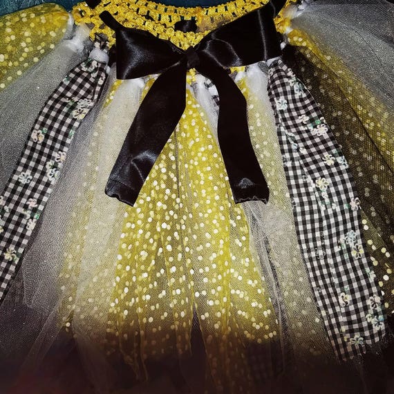 Yellow, white and black tutu with daisy accents. Fits most kids up to 6 yrs old