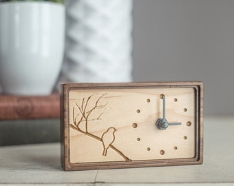Wood clock made of walnut and maple featuring a carved bird on tree branches