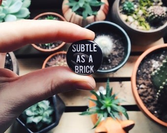 Subtle As A Brick 1" Pinback Button (Brand New, Taking Back Sunday, emo)