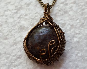 Antiqued wire wrapped speckled black cabochon with antiqued copper chain.