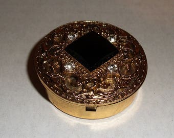 Gold Tone Metal Pill Box with Rhinestones and Black Gem.