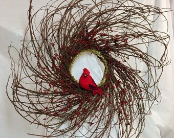 Pip berry cardinal winter wreath. 20" twig frame covered in red pip berries. Gold trim in center. 4" velvet faux cardinal. Chenille hanger
