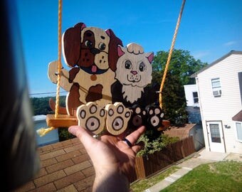 Puppy and kitty sitting on a swing this is a swinger