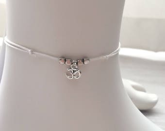 Enkelband. Wit vegan koord met 3OHM bedel. Met schuifknoopjes. One size fits all.