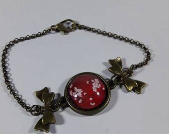 bronze bracelet with cherry blossoms on red background