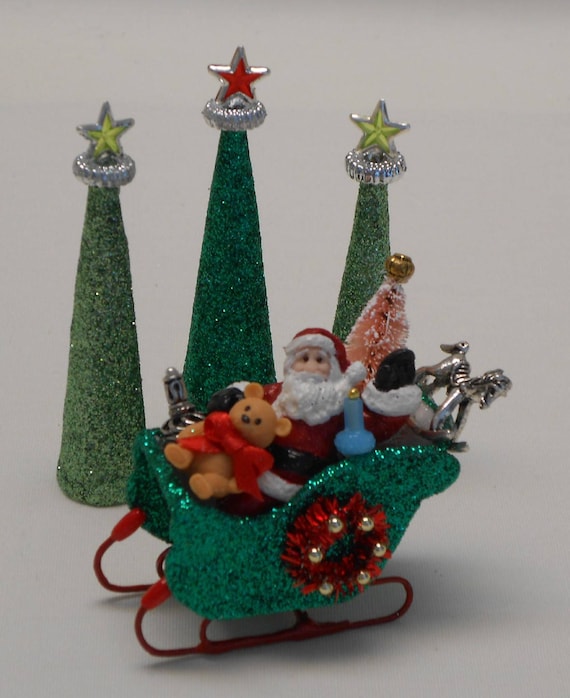 A gorgeeous Santa in his sleigh, ready to deliver presents under the trees - How to Decorate Your Dollhouse For Christmas in 1:12 Scale - Divine Miniatures