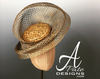 Patricia's Crown - gilded freeform window pane sinamay swirls around a gilded ostrich embossed leather pillbox, accented w feather & bauble