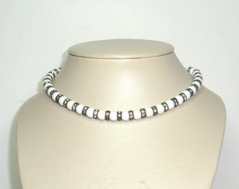 White milk glass beaded necklace with alternating rings of channel set rhinestones. Choker adjustable, 14" to16" strung on silver tone chain