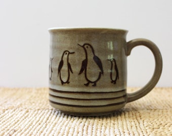 Rustic stoneware coffee mug with penguins.