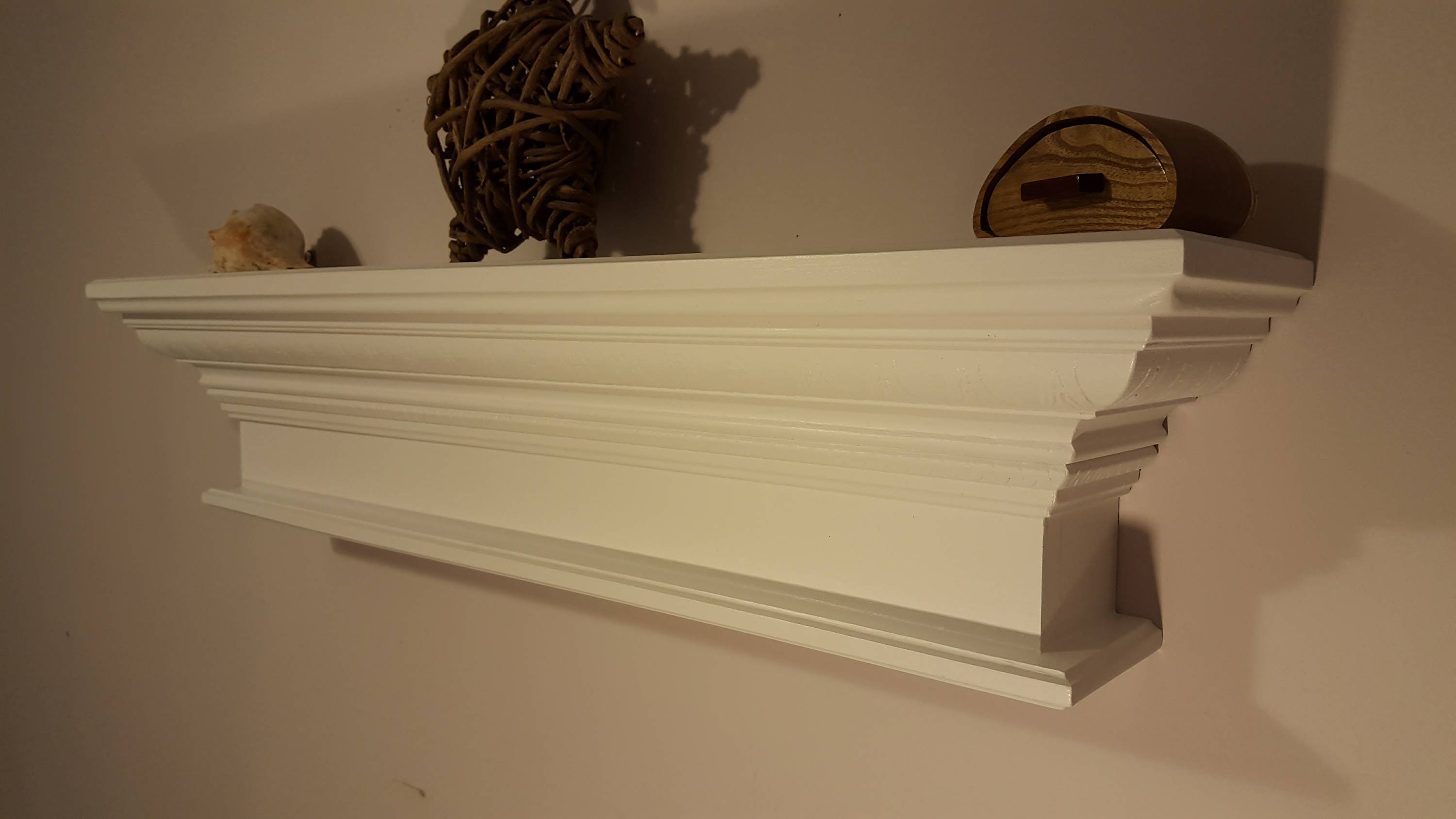 Floating crown molding shelf with decorative design in white