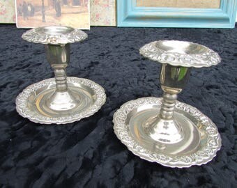 A pair of small white metal candle holders.