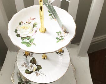 A very pretty mismatched china cake stand with cream and yellow roses