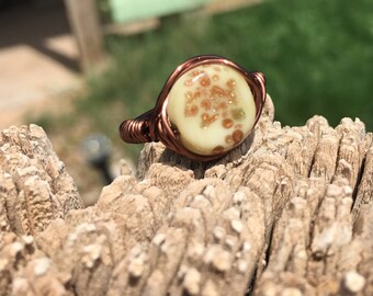 bronze wire wrapped ring with ivory bead accented with metallic copper flakes.