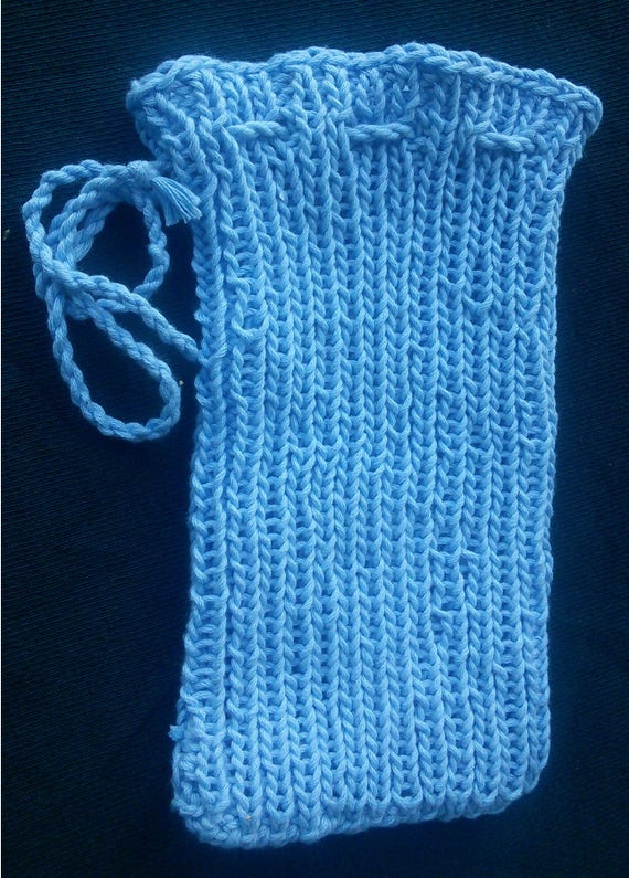 A knit ribbed drawstring bag, knit in pale blue yarn. There is a twisted cord drawstring at the top of the bag