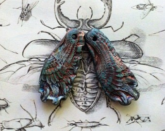 237. Wings of a Dove Two Blue Gold Rust Raku Wing Pendants