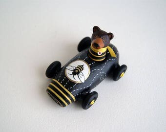 brown bear in a miniature bee car - black and yellow toy car